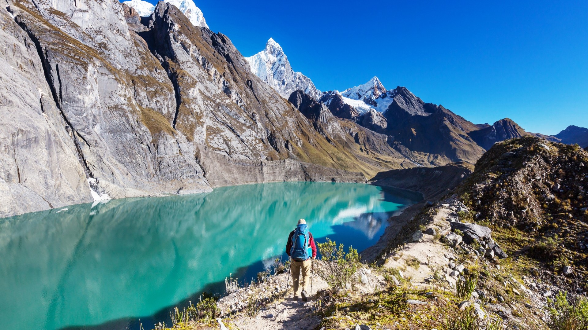 Trekker frente a una laguna turquesa en la Cordillera Blanca, Perú