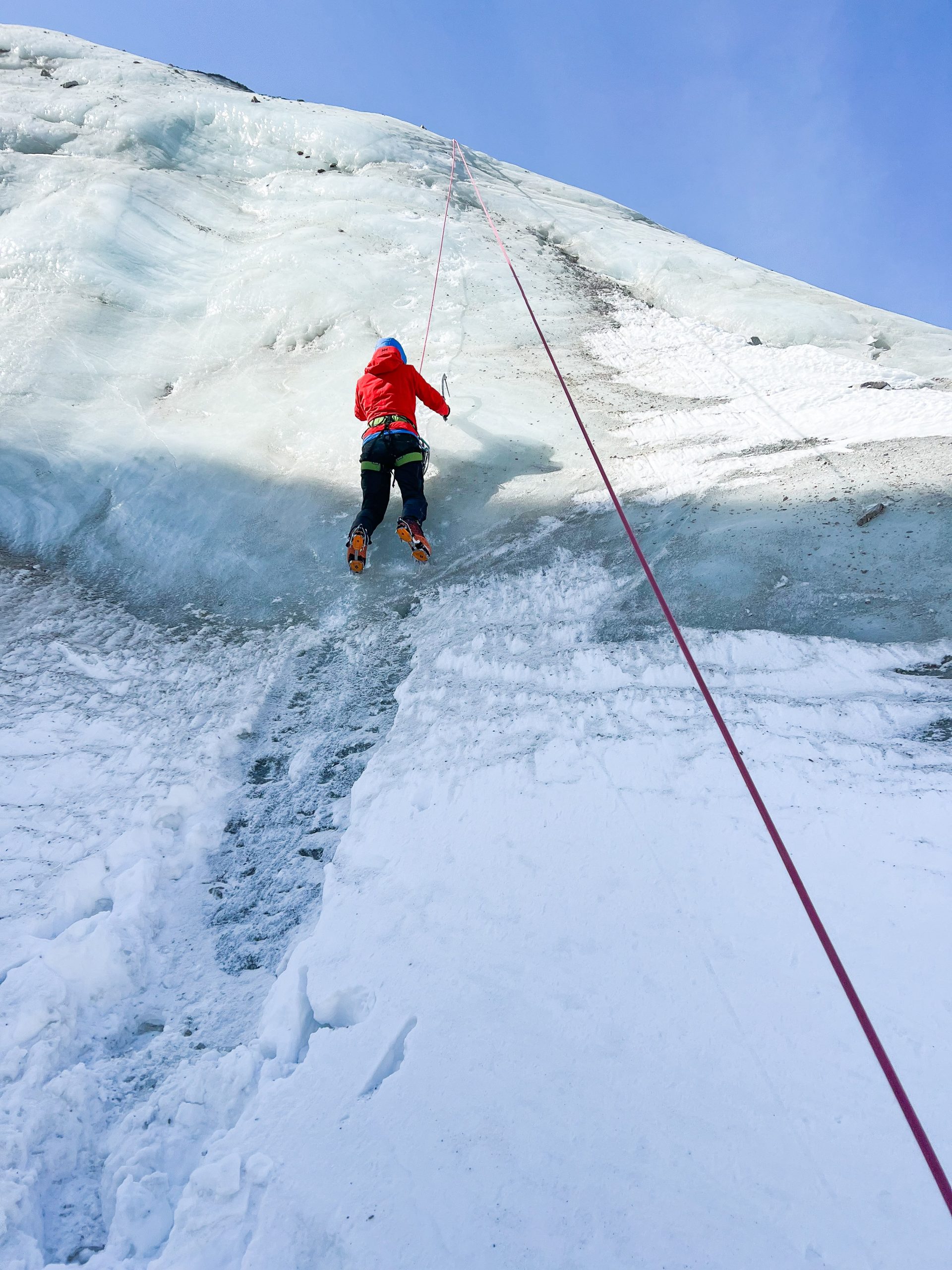 Alumno escalando hielo con crampones y piolet durante el curso en Kirguistán
