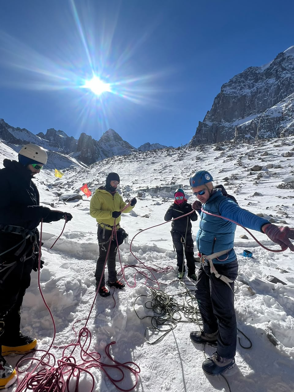 Grupo preparando cuerdas y arneses antes de salir al glaciar, con las montañas del Tien Shan al fondo