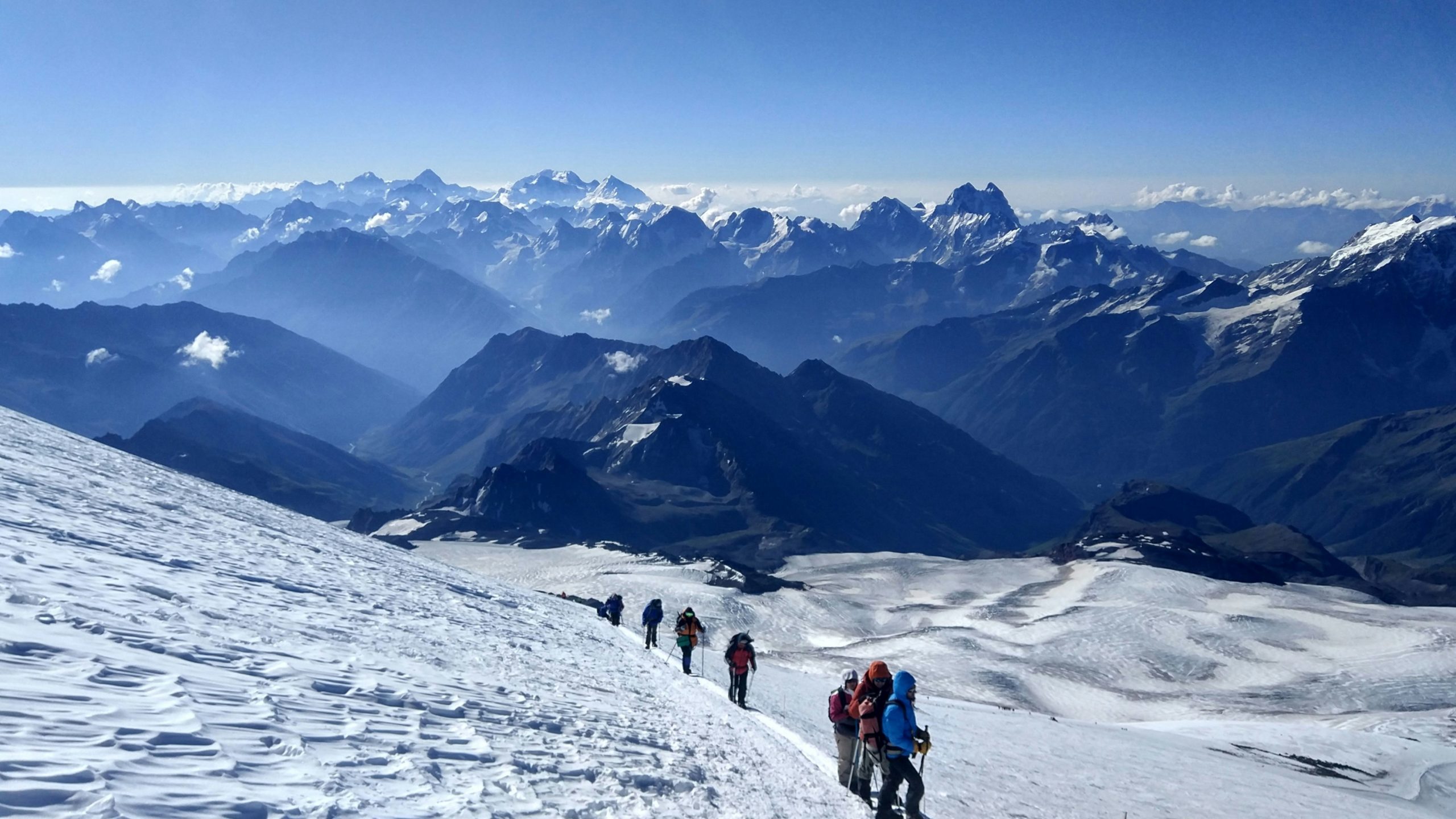 Grupo de alpinistas ascendiendo por la nieve del Elbrus, con el Cáucaso al fondo